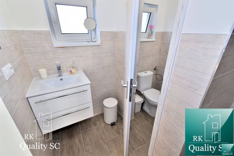Bathroom with a sink, toilet, and wood-patterned floor in a family house.