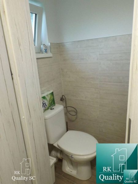 A toilet in a cabin with a wood-patterned floor and beige tiles.