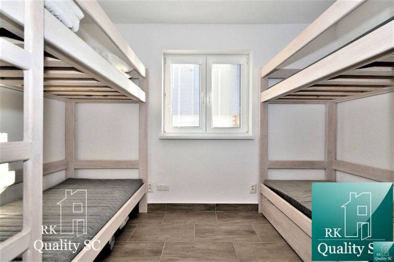 Bunk beds in a cabin with a wooden floor decor and a window with blinds.