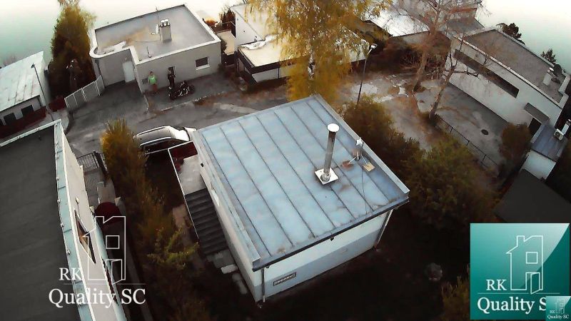 Cottage in Senec at SUNNY LAKES SOUTH, with a flat roof, surrounding trees, and a road.