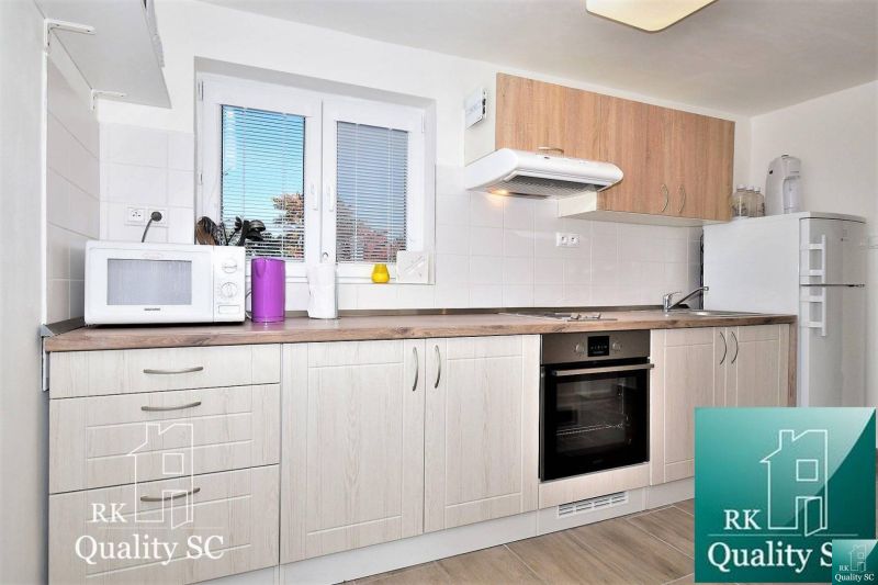 A kitchen in a cottage with a microwave, oven, and wood-patterned flooring.