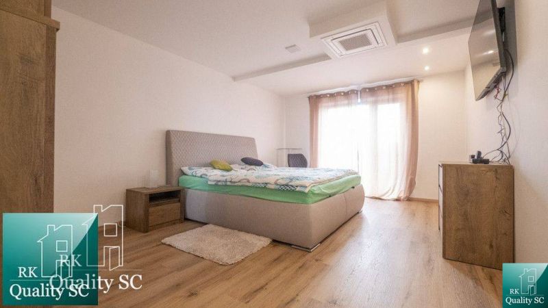 Bedroom with a bed, dresser, nightstands, and wooden decor flooring in a family house.