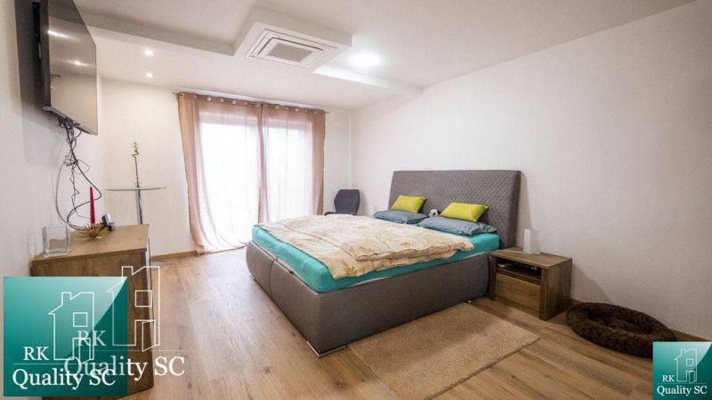 A bedroom in a family house with a wood-decor floor and minimalist furnishings.