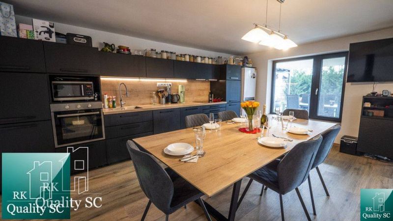 A kitchen in a family house with a large dining table and a floor with a wooden decor.