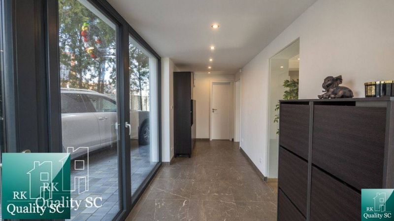 Interior of a family house with a glass corridor and a view of the parking lot.