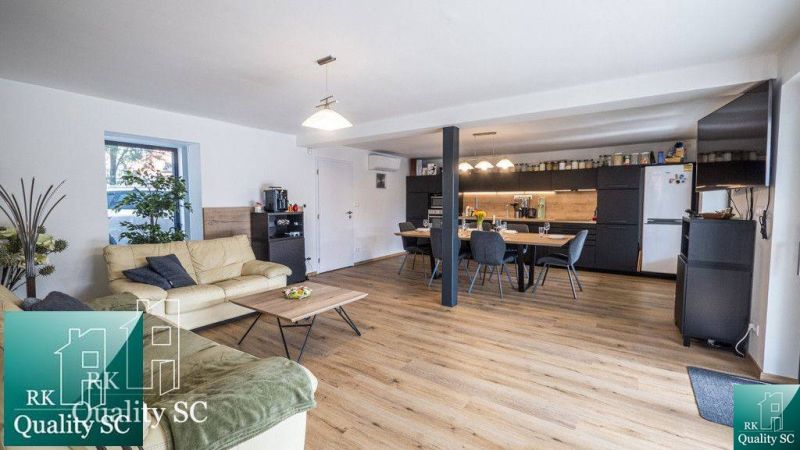 Family house living room with kitchen, wooden decor flooring, comfortable seating.