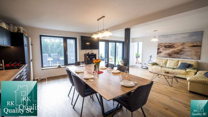 Dining table and sofa with wood-patterned flooring in a family house.