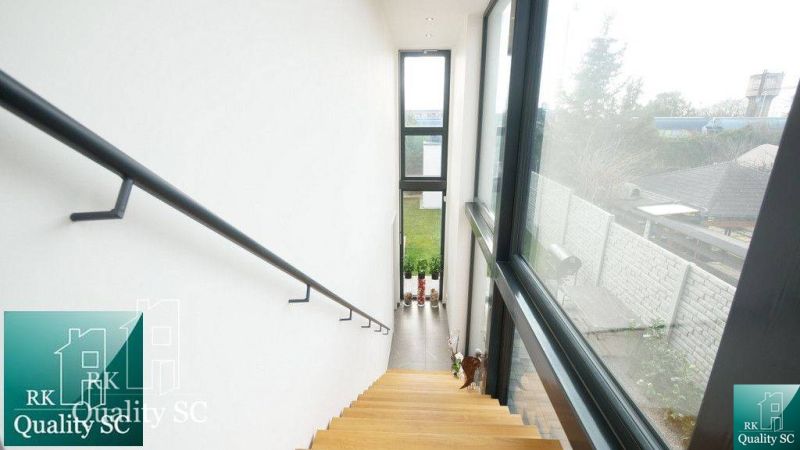 A staircase with a wooden decor in a family house with large windows and a view of the garden.