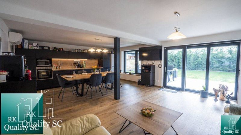 Interior of a family house with wide windows, a kitchenette, and a wooden decor floor.