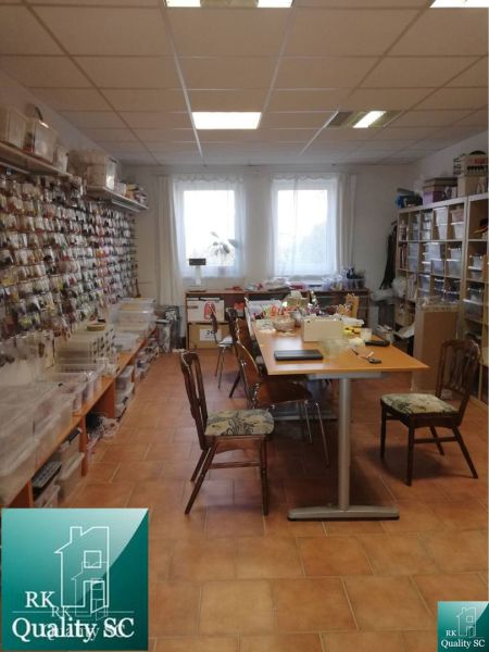 A room in a family house with shelves for materials and a long workbench.