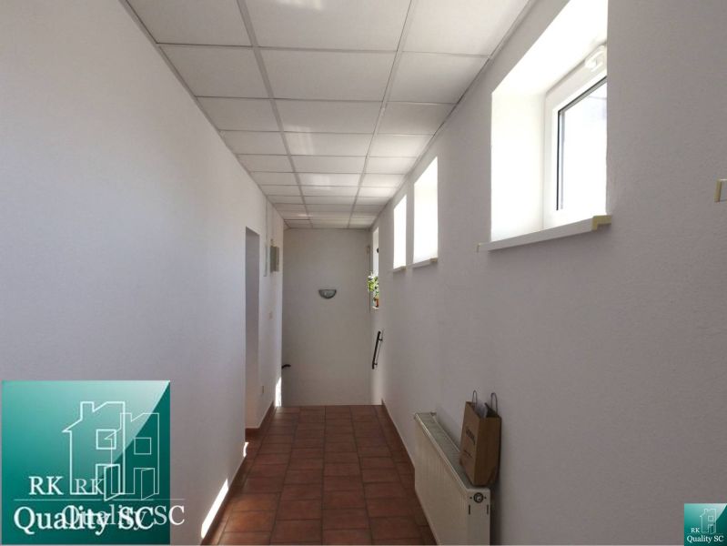 A hallway in a family house with tiles, light walls, and ceiling panels.