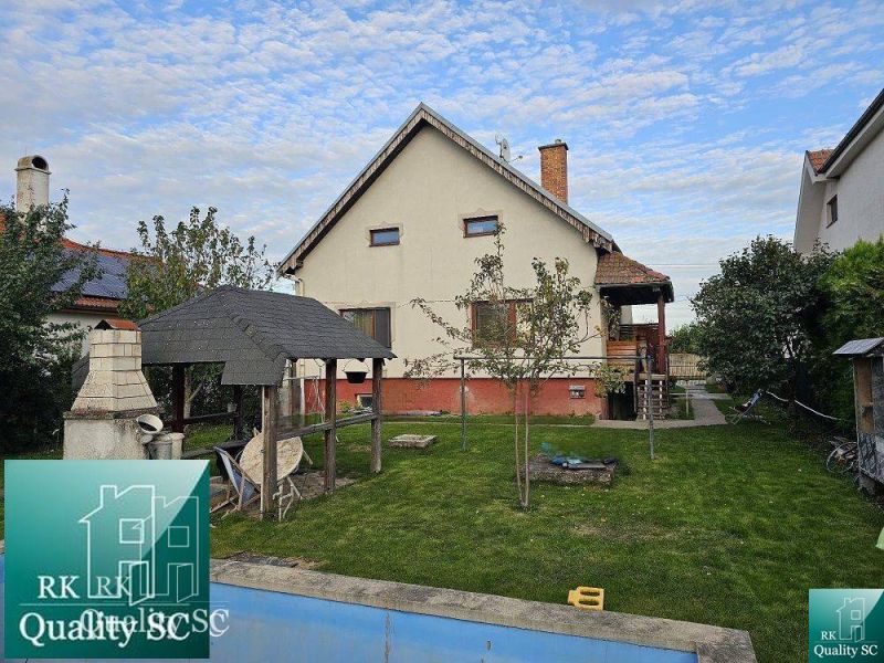 A family house in Turany with a lawn, a gazebo, and an outdoor fireplace in the garden.
