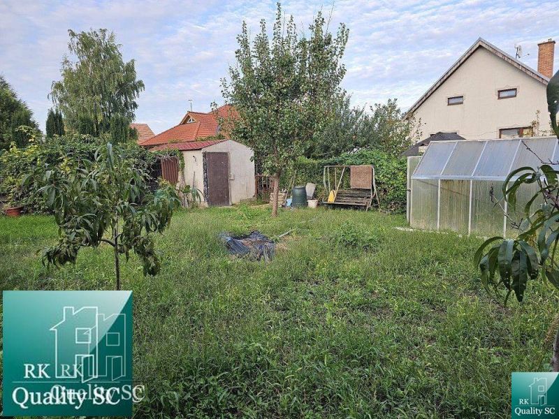 A garden with fruit trees and a greenhouse by a family house on a street in Tureň.