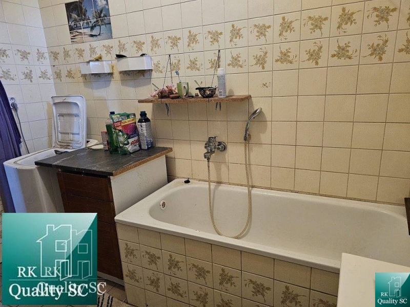 A bathroom with a bathtub in a family house, tiled with floral-patterned tiles.
