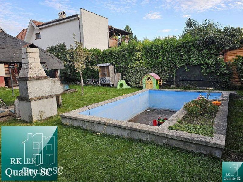 A garden at a family house in Turen with a swimming pool, a fireplace, and a children's playhouse.