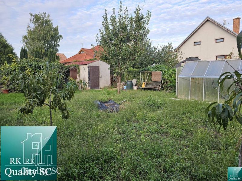 The garden of a family house in the village of Tureň with a lawn, greenhouse, and trees.