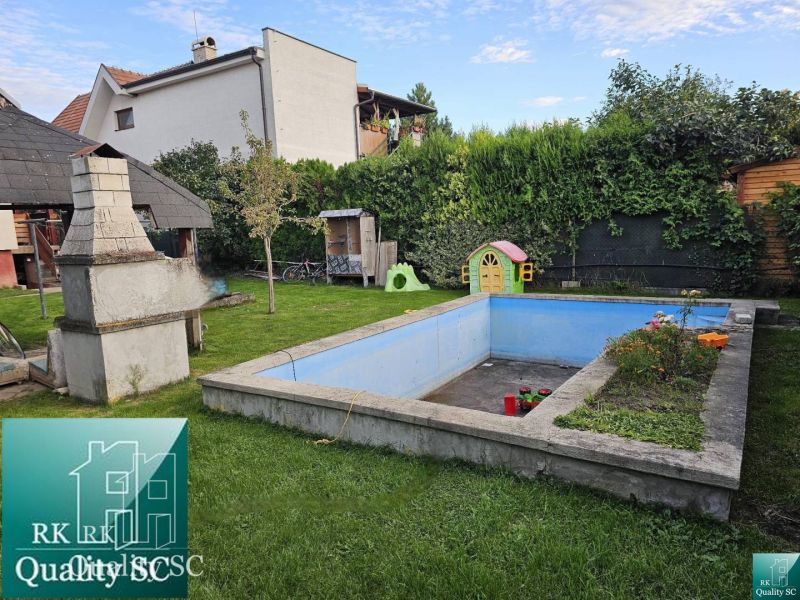 The garden of a family house in Tureň with a gazebo, a swimming pool, and a children's playhouse.