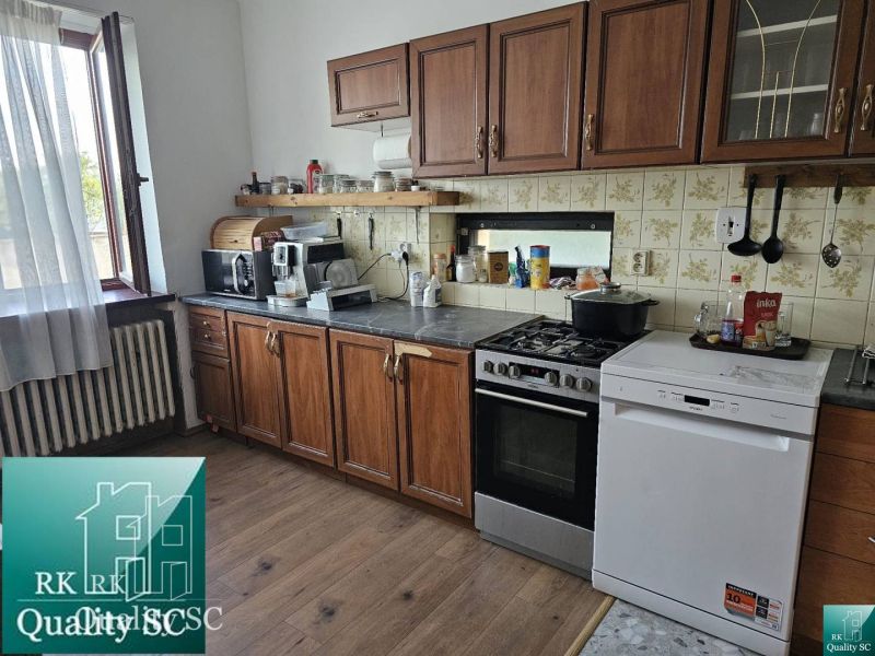 A kitchen in a family house with wooden decor floors, kitchen appliances, and a window.