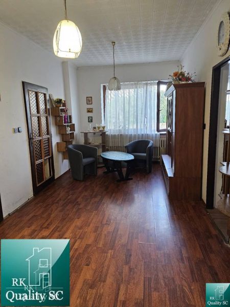 Interior of a family house with a wooden decor floor, armchairs, and a coffee table.
