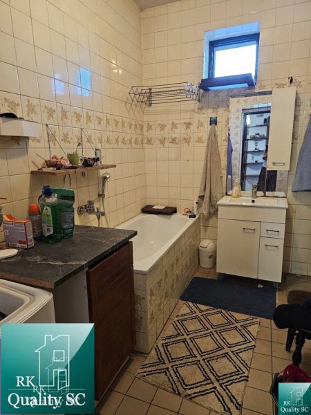 Bathroom in a family house with a bathtub, cabinet, and tiles on the walls.
