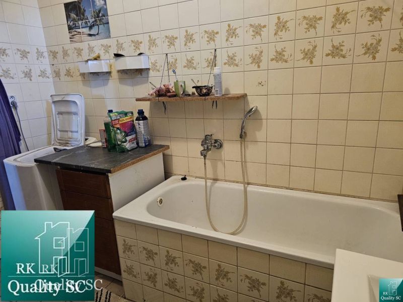 A family house bathroom with a bathtub and a washing machine, decorative tiles with flowers.