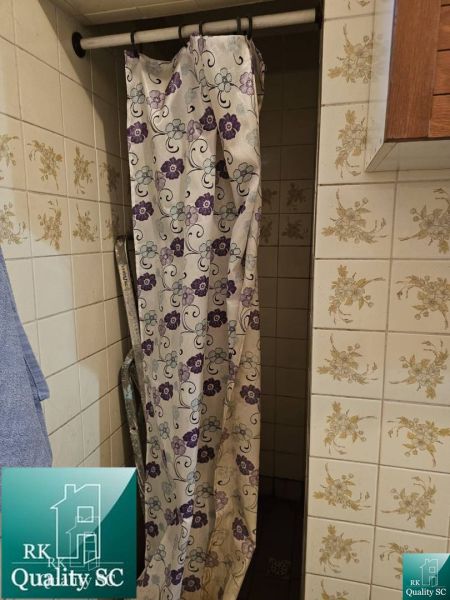 A shower corner with a floral curtain and tiles in a family house.