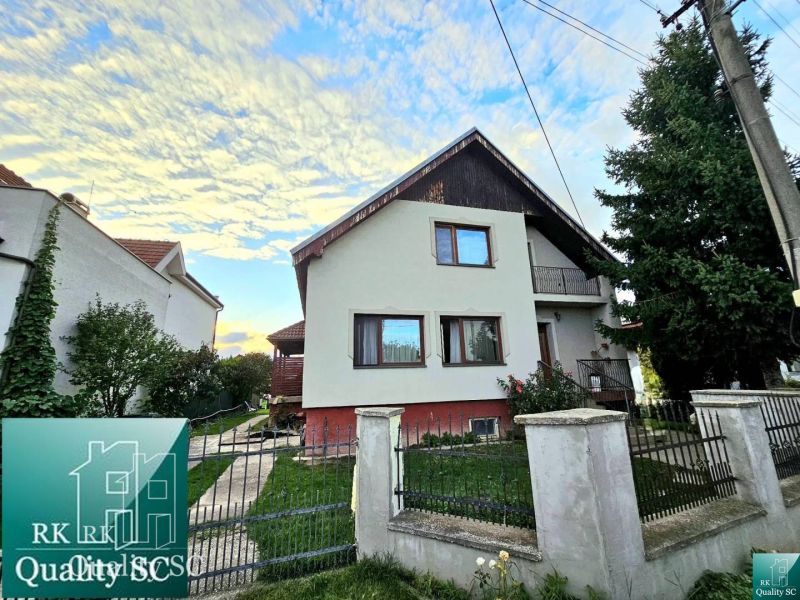 A family house in Tureň on Tureň Street with a fenced garden and a blue sky.