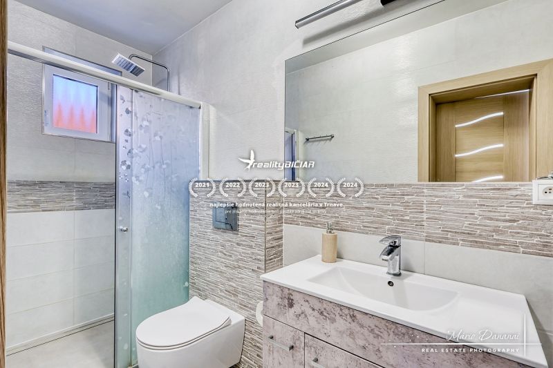 A compact bathroom with a toilet and a shower in a family house, decorated with mosaic tiles.
