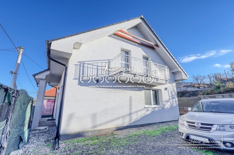 A family house in Hrnčiarovce nad Parnou with a white facade and a balcony on a gravel yard.