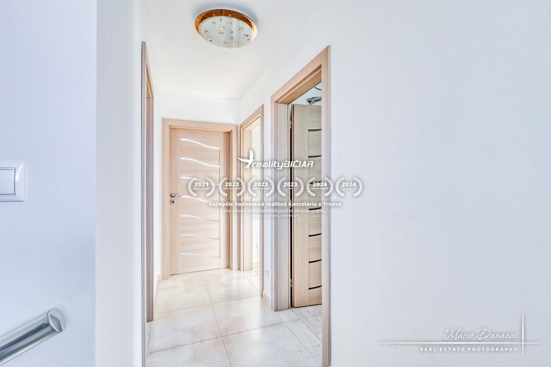 A hallway in a family house with tiles, wooden doors, and stylish lighting.