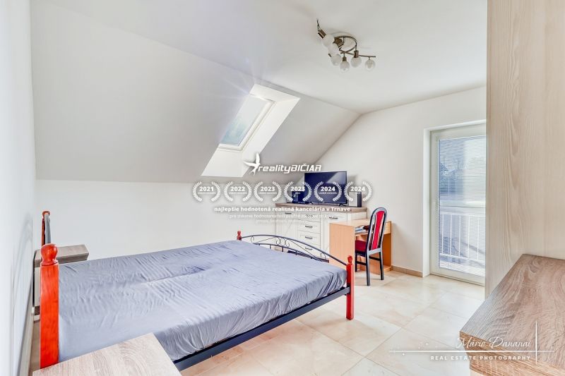 An attic bedroom in a family house with simple furniture and a skylight.
