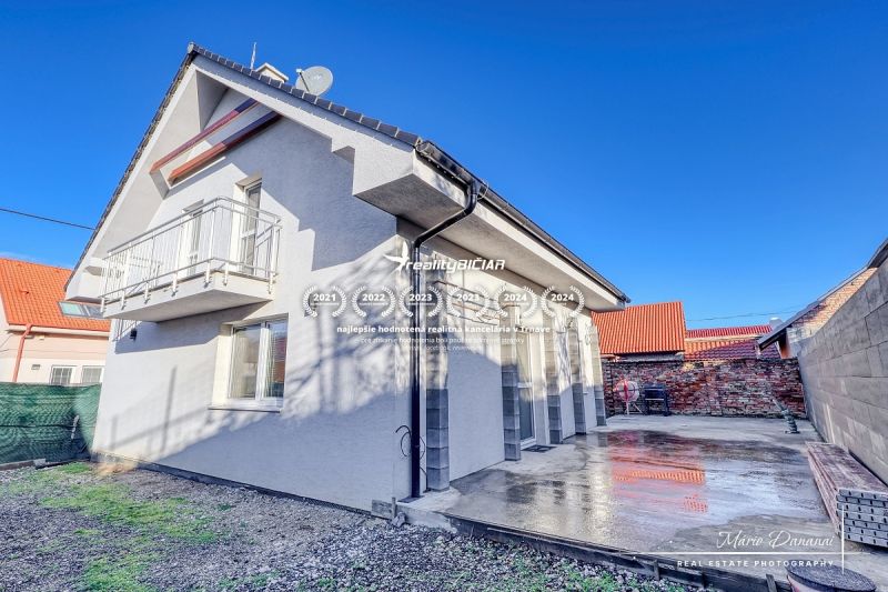 A family house in Hrnčiarovce nad Parnou with a concrete terrace and a balcony on the upper floor.