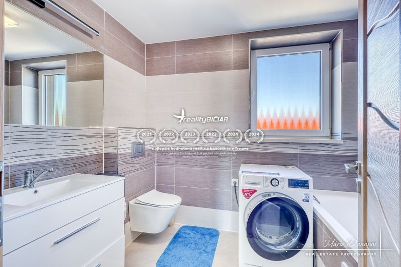 A bathroom in a family house with a washing machine, a sink, and a window with frosted glass.