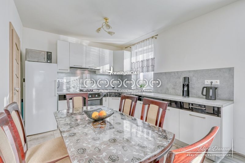 A kitchen in a family house with white cabinets, a table, and appliances.