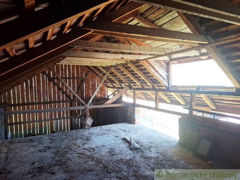 Attic space of a family house with roof beams and a window for lighting.