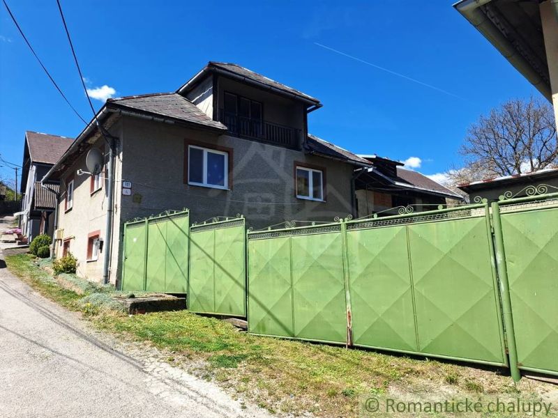 A family house in Heľpa with a large green gate on a sunny street.