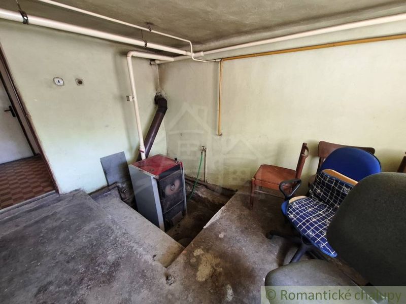 An old boiler room in a family house with office chairs and piping on the wall.
