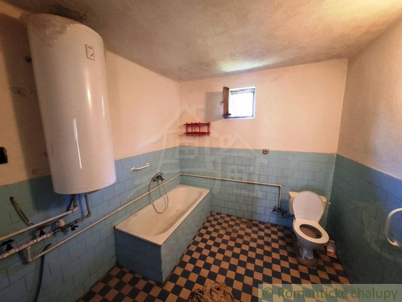 Bathroom in a family house with a bathtub and a water heater.