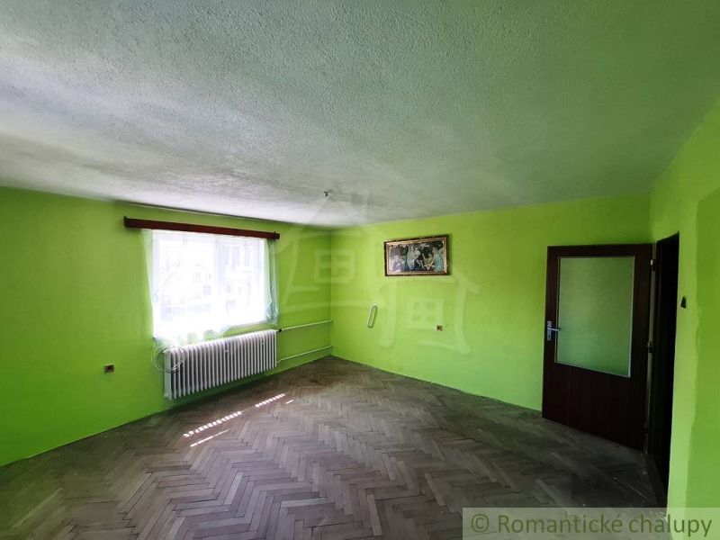 Green walls and a wooden decor floor in a family house, with sunlight streaming through the window.