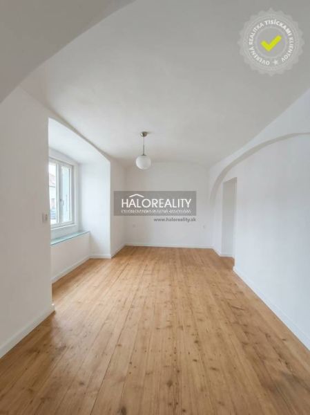 A bright room with an arched ceiling and a wooden decor floor in a three-room apartment.