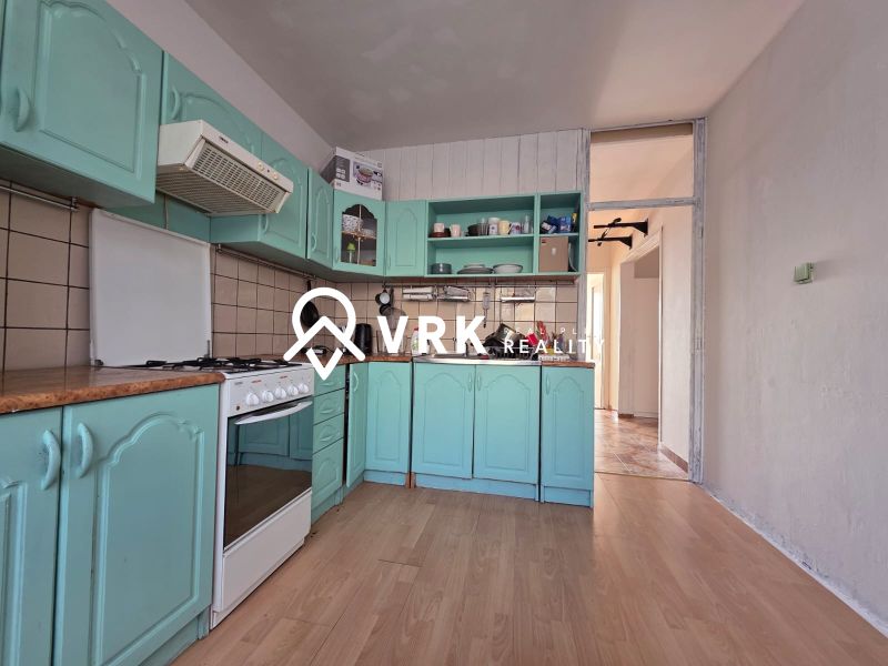 A kitchen with green cabinets and a wooden decor floor in a 4-room apartment.