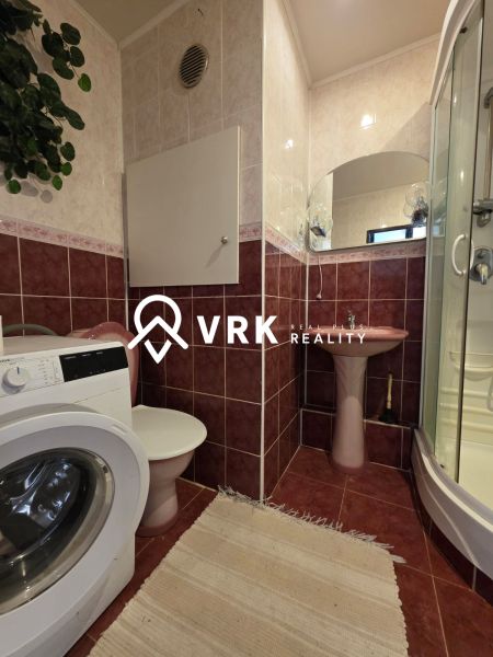 Bathroom with a shower, washing machine, and sink in a 4-room apartment.