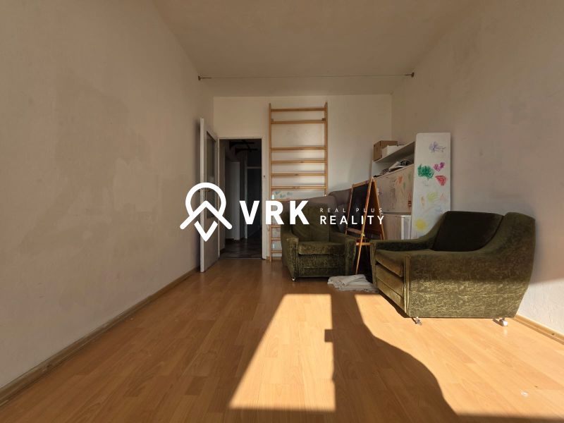 A room in a 4-room apartment with a wooden decor floor and green armchairs.