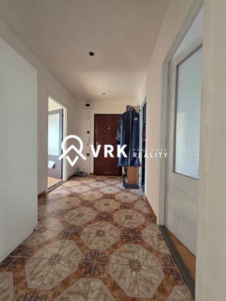 A hallway with ceramic tiles in a 4-room apartment with two doors and a coat rack on the wall.