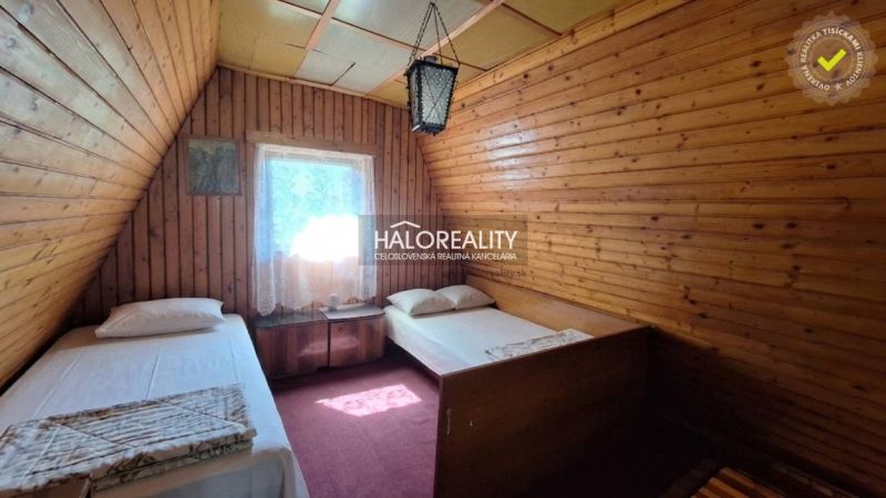A wooden room with two beds in a cottage. Dim lighting and carpets.