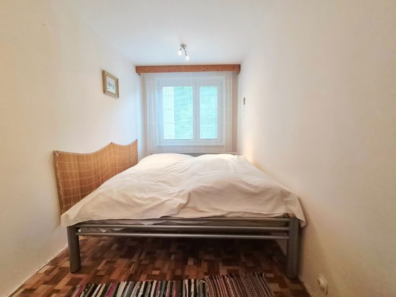 A bedroom in a 2-room apartment with a double bed and a wooden decor floor.