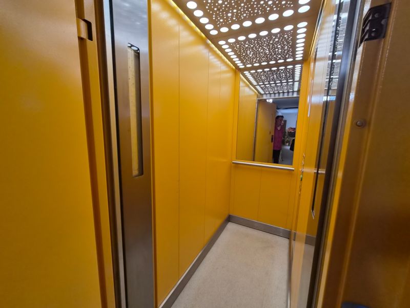Elevator with bright yellow walls and a mirror.