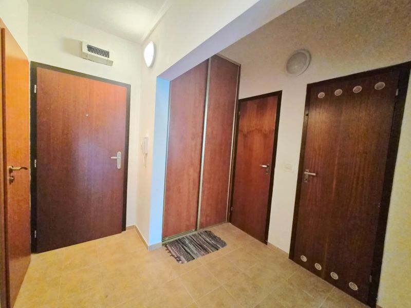 Hallway in a 2-room apartment with wooden doors and tiled floor.