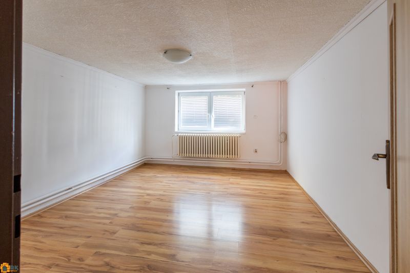 A room in a family house with a wooden decor floor and a central radiator.