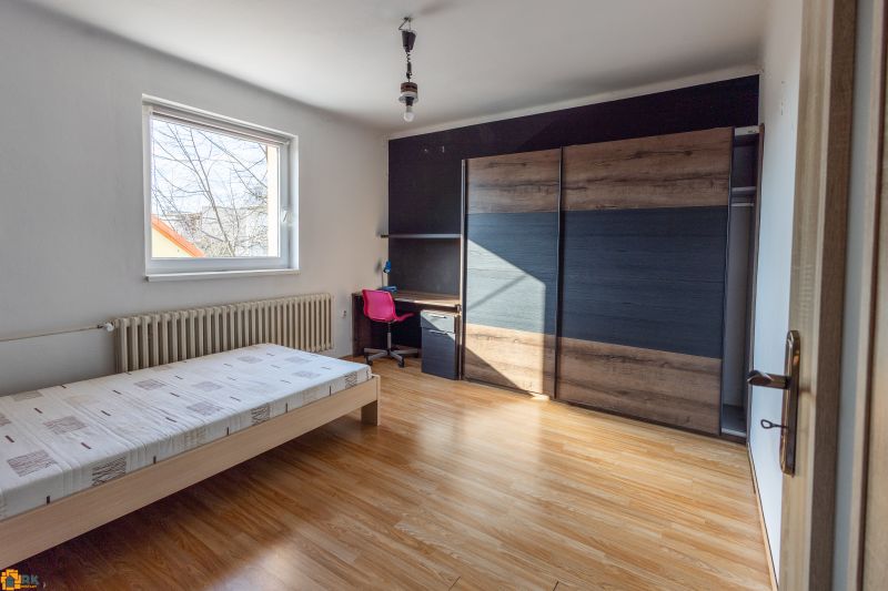 A room in a family house with a bed, a wardrobe, and a floor with a wooden decor.